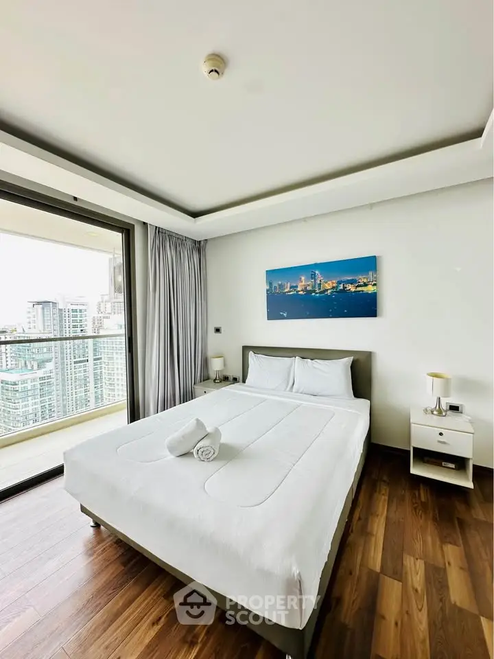 Modern bedroom with city view and balcony access in high-rise apartment
