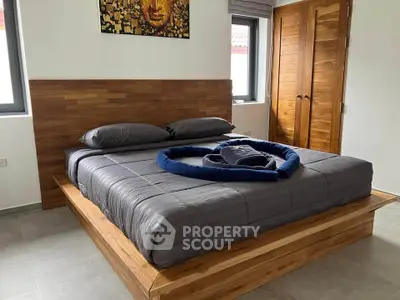 Modern bedroom with wooden bed frame and stylish decor, featuring cozy bedding and natural light.