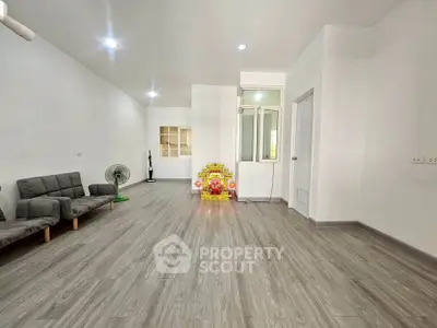 Spacious minimalist living room with modern flooring and simple furnishings.
