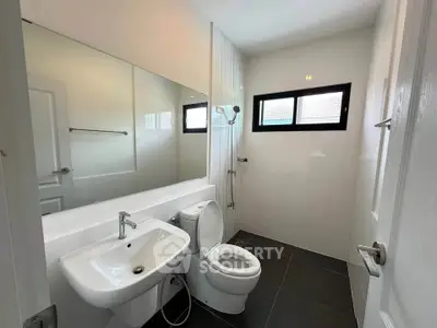 Modern bathroom with sleek fixtures and large mirror, featuring a window for natural light.