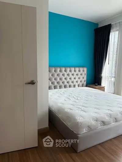 Modern bedroom with stylish tufted headboard and vibrant blue accent wall.