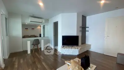 Modern living room with sleek design and wooden flooring, featuring a TV and dining area.
