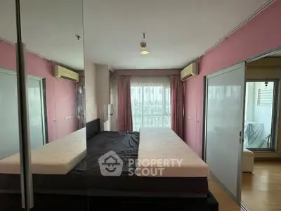 Spacious bedroom with large windows and mirrored closet doors in modern apartment.