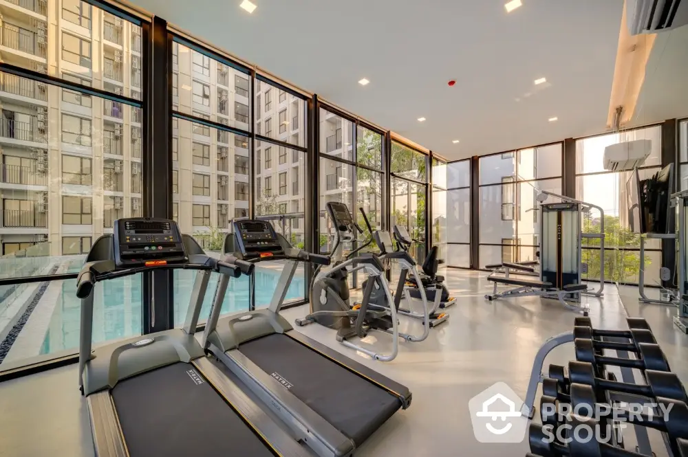 Modern gym with state-of-the-art equipment and pool view in luxury apartment complex.