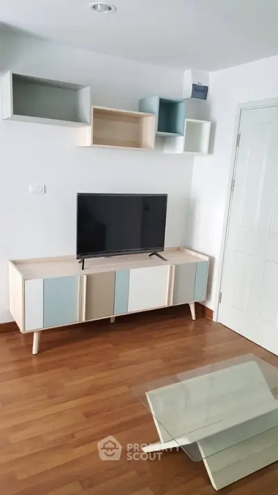 Modern living room with stylish TV stand and wall-mounted shelves, featuring sleek wooden flooring.