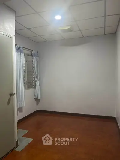 Spacious empty room with wooden flooring and window, ideal for customization.