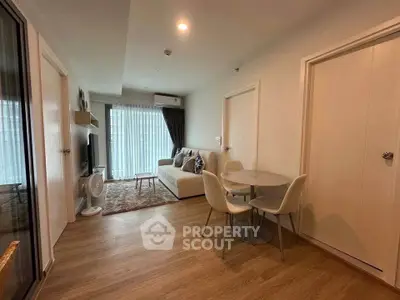 Modern living room with cozy seating and dining area, featuring elegant decor and natural light.