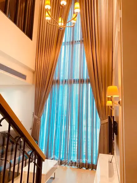 Luxurious high-ceiling living room with elegant drapes and modern lighting.