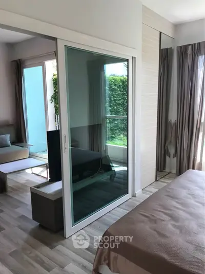 Modern bedroom with sliding glass doors and garden view, featuring stylish decor and natural light.