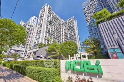Modern high-rise condominium with lush greenery and clear blue sky