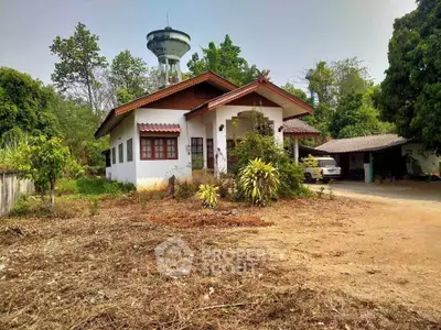 Charming countryside house with lush greenery and spacious driveway, perfect for serene living.