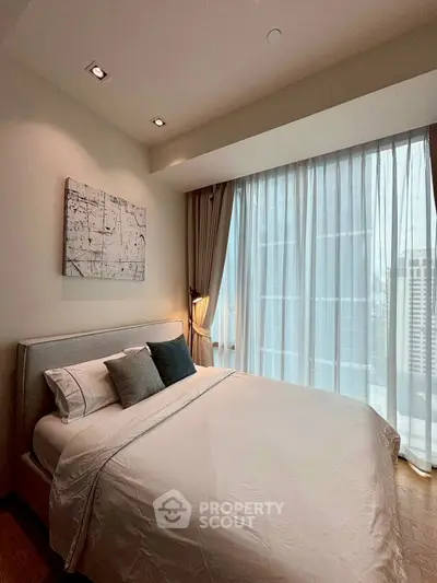 Luxurious bedroom with large window and modern decor in high-rise apartment.