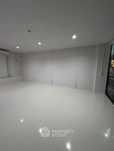 Spacious empty room with glossy white tiles and modern lighting, perfect for customization.