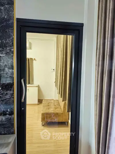 Modern interior view through a glass door showcasing a cozy seating area with elegant curtains.