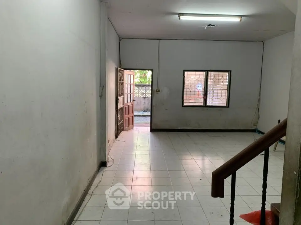 Spacious interior with tiled flooring and natural light, ideal for renovation.