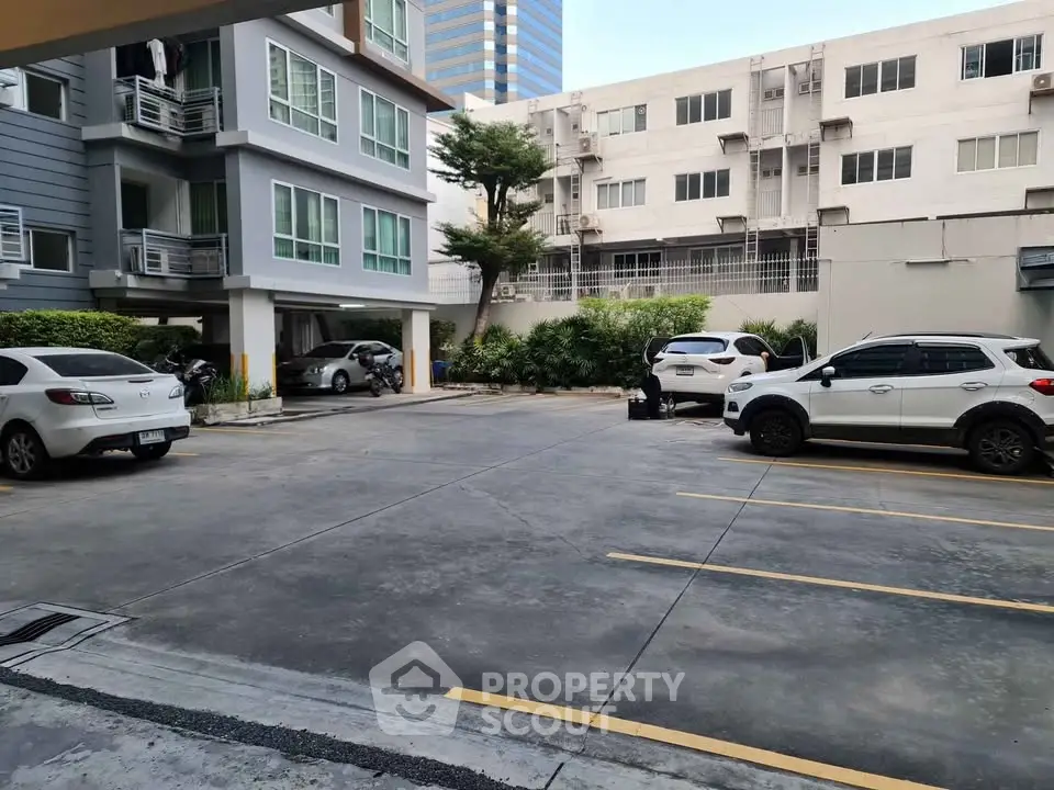 Spacious parking area in modern residential complex with multiple parking spaces and surrounding greenery.