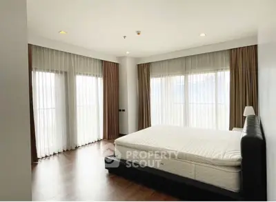 Spacious bedroom with large windows and elegant curtains in modern apartment