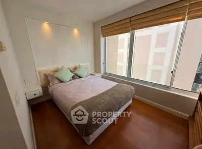 Cozy bedroom with large window and wooden flooring in modern apartment