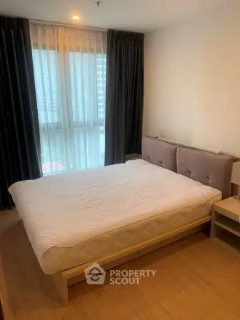 Spacious bedroom with modern decor and large window for natural light.