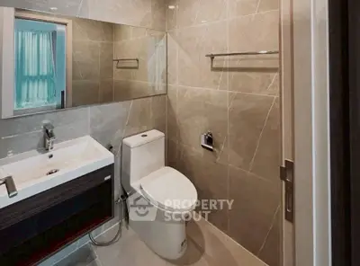 Modern bathroom with sleek fixtures and elegant tile design, featuring a spacious mirror and contemporary sink.