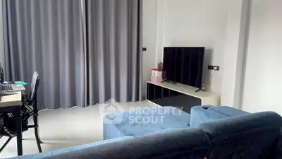 Modern living room with blue sofa and large TV, perfect for relaxation and entertainment.