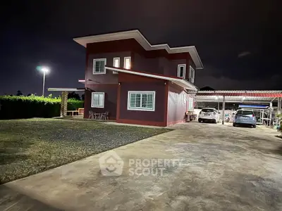 Spacious two-story home with ample parking and outdoor seating area at night.