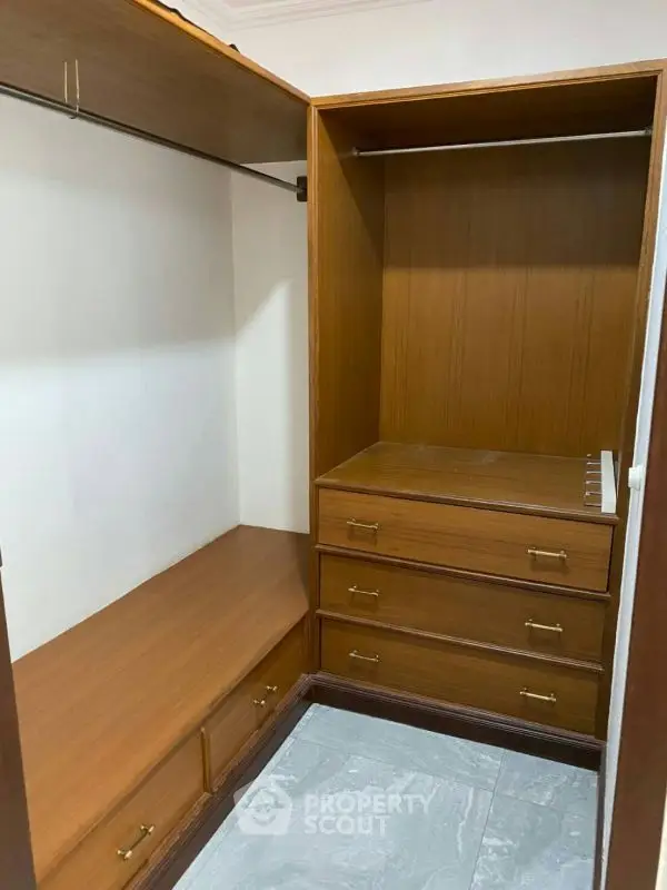 Spacious walk-in closet with wooden shelves and drawers, perfect for organized storage.