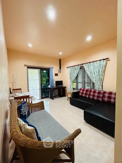 Cozy living room with natural light, stylish furniture, and access to a balcony with a view.