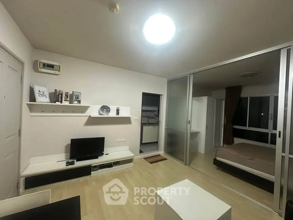 Modern studio apartment with open layout, featuring a cozy living area and bedroom separated by sliding glass doors.