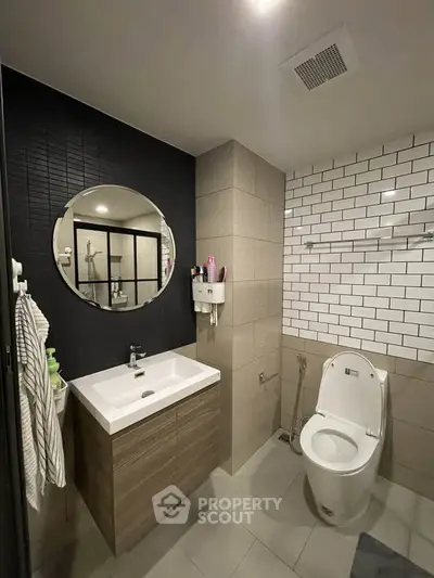 Modern bathroom with sleek design, featuring a round mirror, stylish sink, and contemporary fixtures.