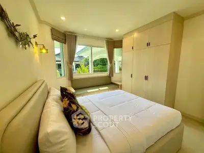 Bright and cozy bedroom with large window and built-in wardrobe, perfect for relaxation.