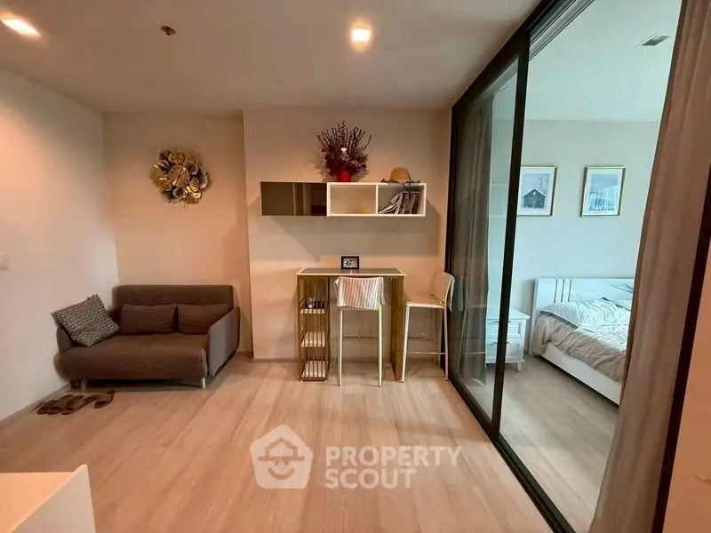 Modern apartment interior with cozy living area and bedroom separated by glass sliding doors.