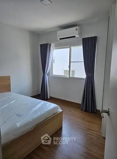 Bright and cozy bedroom with wooden flooring and air conditioning