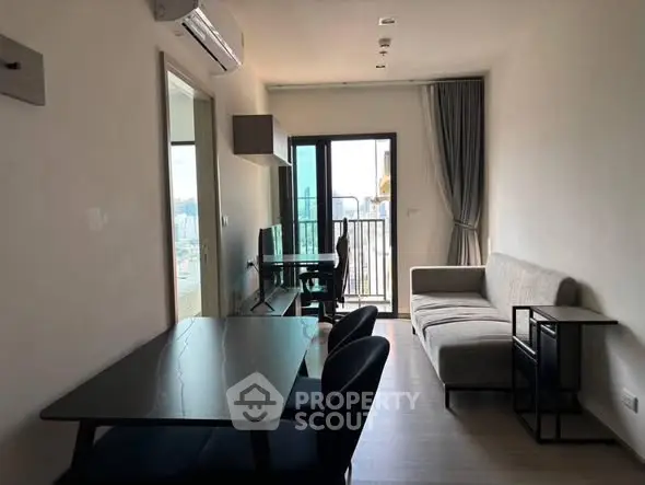 Modern living room with balcony view, sleek furniture, and natural light.