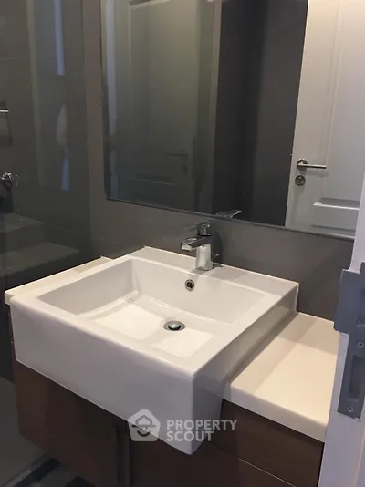 Modern bathroom with sleek sink and mirror in contemporary apartment.