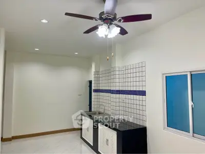 Modern kitchen with ceiling fan and tiled backsplash in a bright interior.