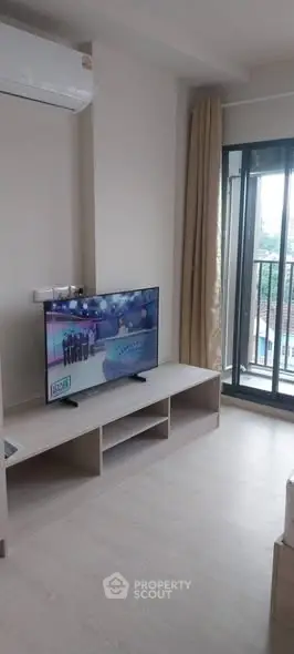 Modern living room with TV and balcony view, featuring sleek design and natural light.