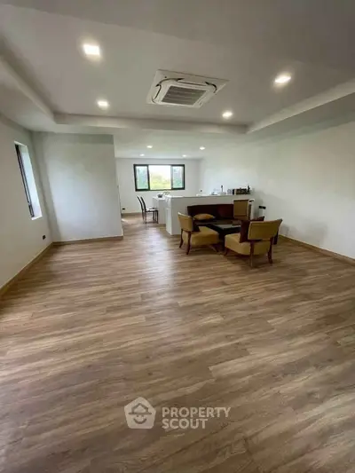 Spacious open-plan living area with wooden flooring and modern ceiling lights.