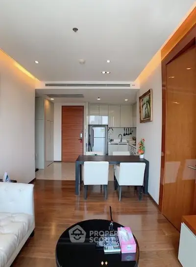 Modern living room with open kitchen, wooden flooring, and stylish furniture in a contemporary apartment.