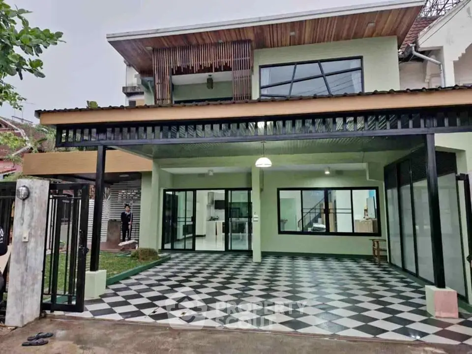 Modern two-story house with spacious checkered patio and large glass doors