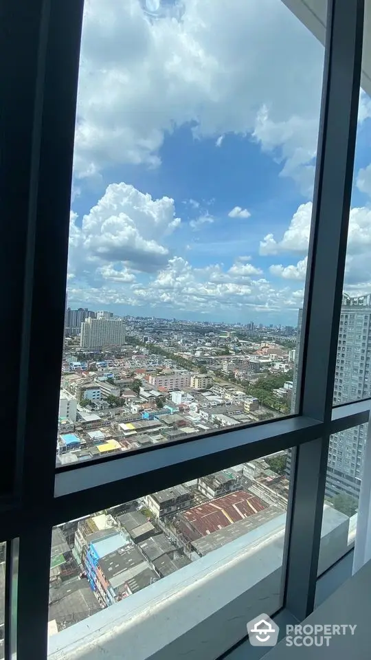 Stunning high-rise city view from a modern apartment window, showcasing urban landscape and blue skies.