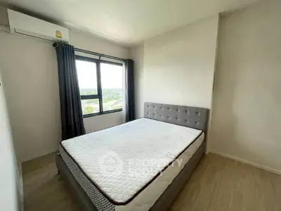 Bright bedroom with large window and modern bed, offering a serene view and ample natural light.