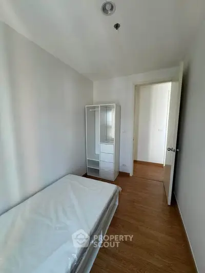 Cozy minimalist bedroom with wooden flooring and compact wardrobe