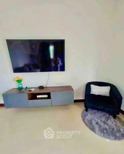 Modern living room with wall-mounted TV and cozy seating area.