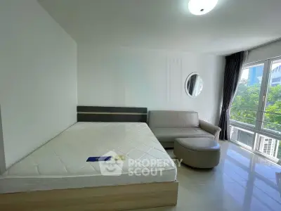 Spacious bedroom with modern furnishings and large window offering natural light and city view.