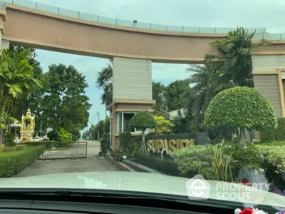 Luxurious gated entrance with lush greenery and modern architecture