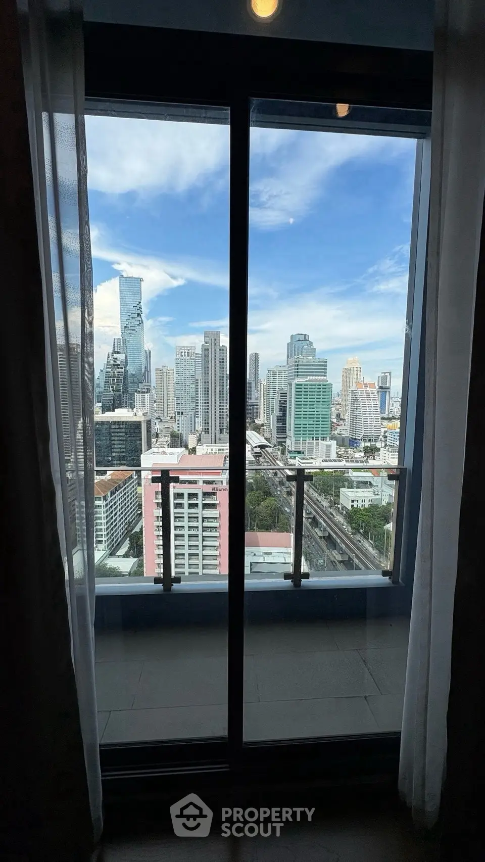 Stunning cityscape view from a high-rise balcony with glass doors, perfect for urban living.