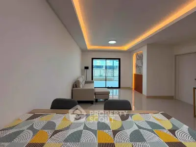 Modern living room with stylish ceiling lights and cozy seating area, featuring a vibrant patterned tablecloth.