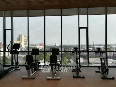 Spacious gym with panoramic city views and modern exercise equipment.