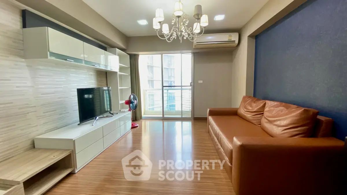 Spacious living room with modern decor and balcony access in urban apartment.